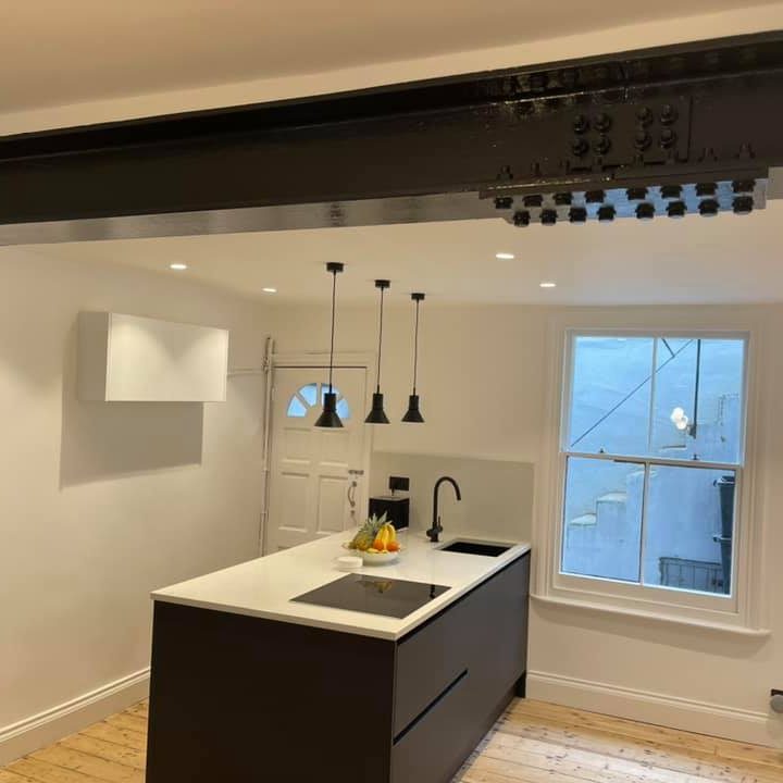 Brighton an Hove House Extension Modern kitchen and living area with large skylights, white cabinets, and a red chair. In Brighton,Hove, Sussex area.